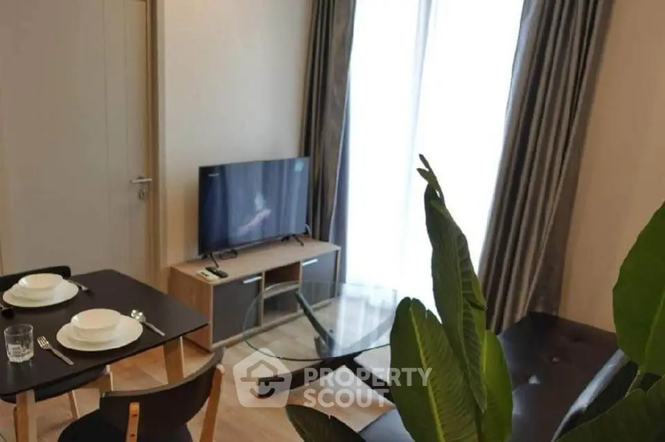 Modern living room with TV, dining table, and large window for natural light.