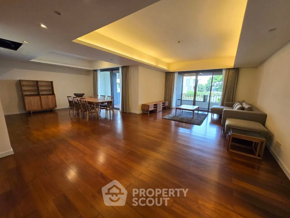 Spacious living room with wooden flooring and modern furniture in a luxury apartment.