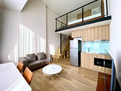 Modern loft apartment with open kitchen and stylish living area, featuring high ceilings and natural light.
