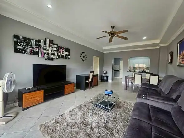 Spacious living room with modern decor and large TV, perfect for relaxation.