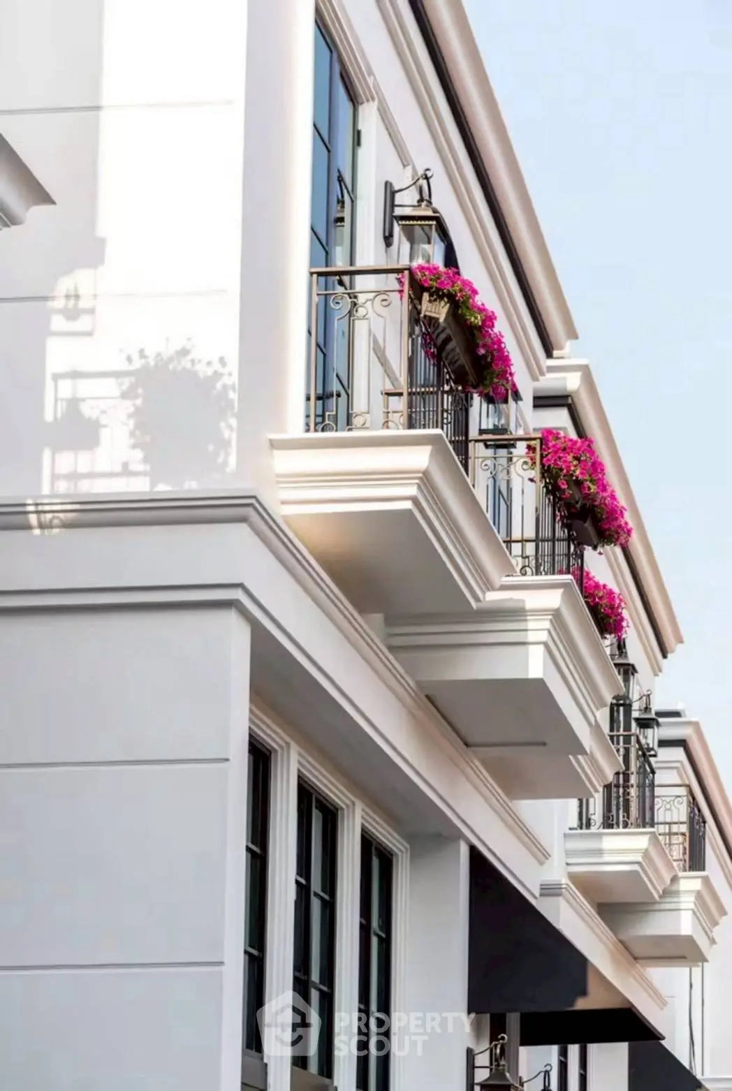 Elegant building exterior with charming balconies adorned with vibrant flowers, showcasing modern architectural design.
