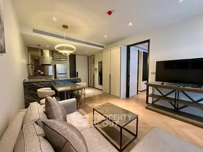 Modern living room with open kitchen, stylish furniture, and elegant lighting.