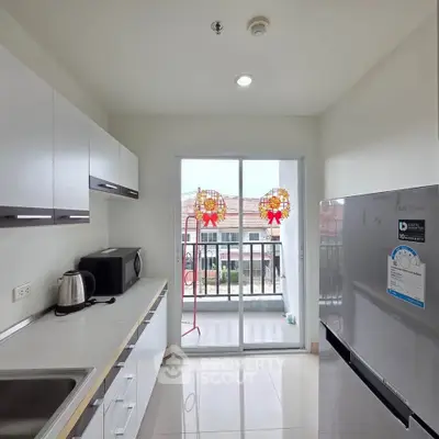 Modern kitchen with balcony view, sleek cabinets, and appliances in a bright, airy space.