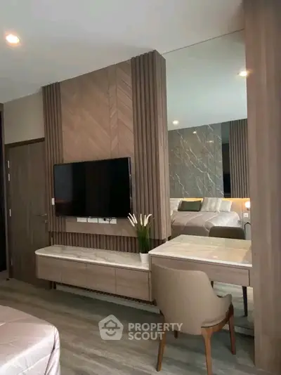 Luxurious bedroom with modern decor and elegant furnishings, featuring a wall-mounted TV and stylish vanity area.