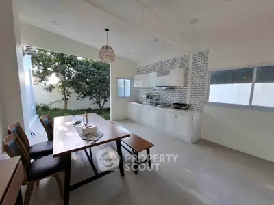Spacious kitchen with open layout and garden view, featuring modern dining area and sleek cabinetry.