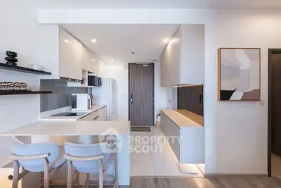 Modern kitchen with sleek design and open layout, featuring stylish bar stools and contemporary decor.
