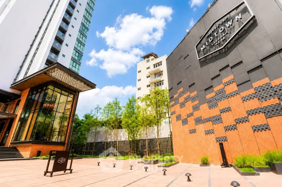 Modern high-rise building with stylish facade and lush greenery in urban setting.