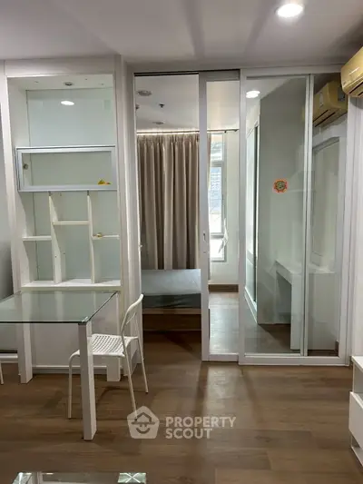 Modern apartment interior with glass partition and wooden flooring, featuring a cozy bedroom and stylish furniture.