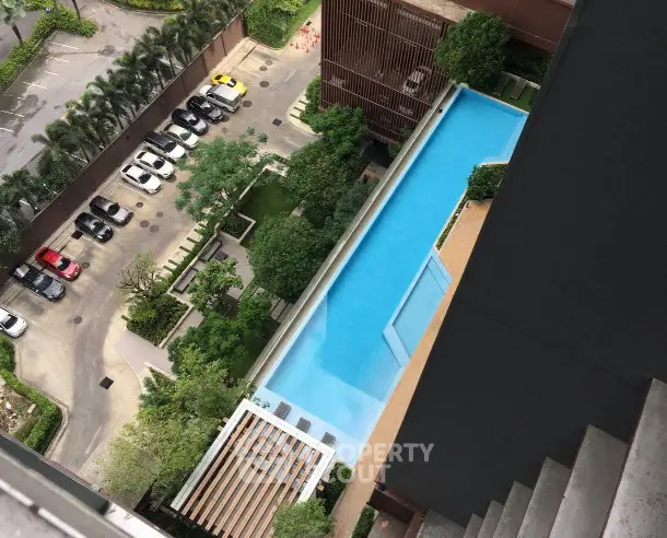 Stunning aerial view of modern apartment complex with large swimming pool and lush greenery.