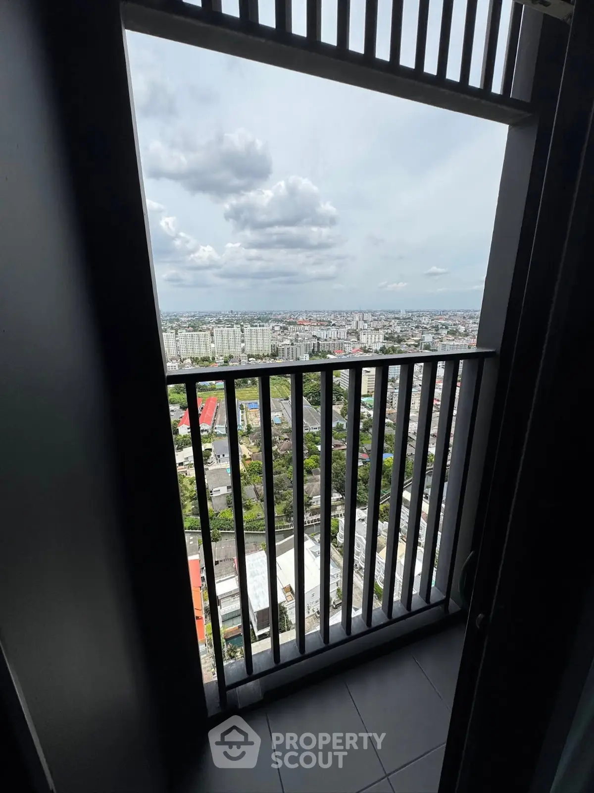 Stunning high-rise balcony view overlooking cityscape with expansive skyline and lush greenery.