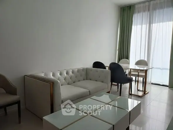 Modern living room with elegant white sofa and dining area, featuring floor-to-ceiling windows.