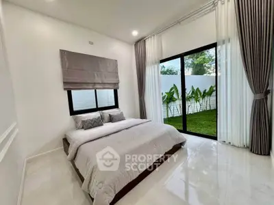 Spacious bedroom with large windows and garden view, featuring elegant curtains and modern decor.