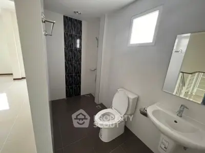 Modern bathroom with sleek design, featuring a toilet, sink, and shower area with stylish tiles.