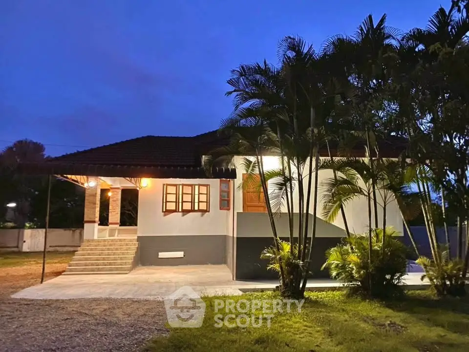 Charming single-story house with lush garden and evening lighting, perfect for serene living.