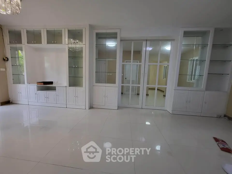Spacious living room with elegant built-in cabinets and glossy white flooring