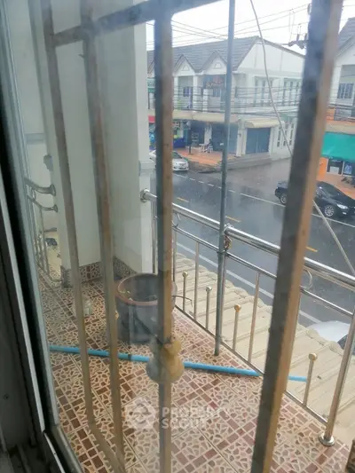 Charming balcony view with tiled flooring overlooking a rainy street scene, perfect for urban living.