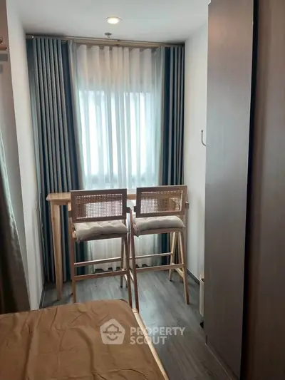 Cozy bedroom with modern decor and natural light, featuring a small dining area by the window.