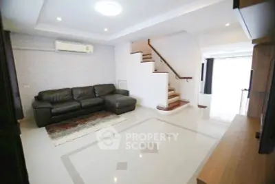 Spacious living room with modern staircase and sleek leather sofa