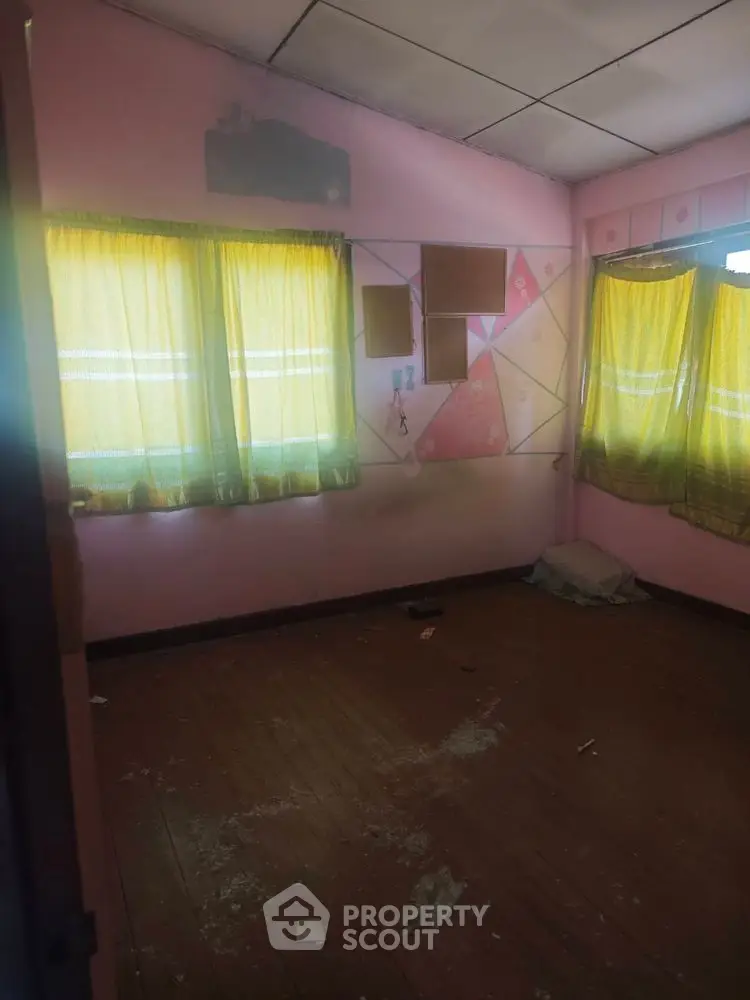 Cozy room with wooden floors and colorful curtains, perfect for creative renovation.