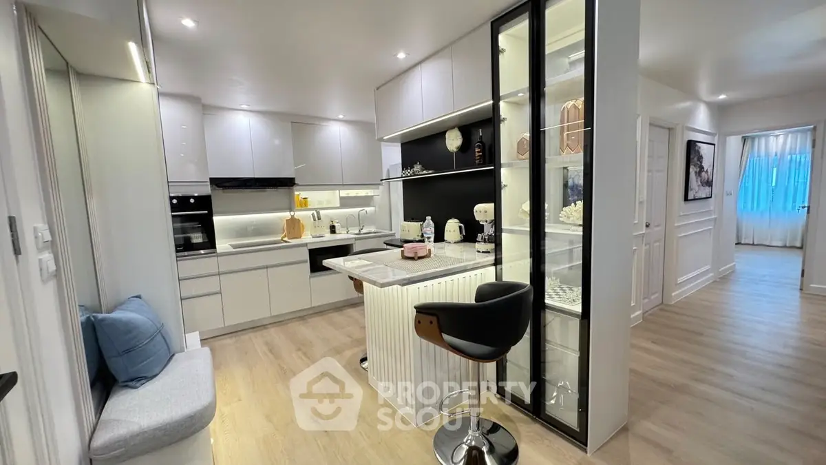 Modern kitchen with sleek white cabinets and stylish breakfast bar in a contemporary apartment.