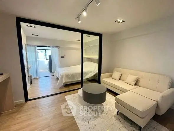 Modern studio apartment with glass partition, cozy living area, and stylish bedroom.