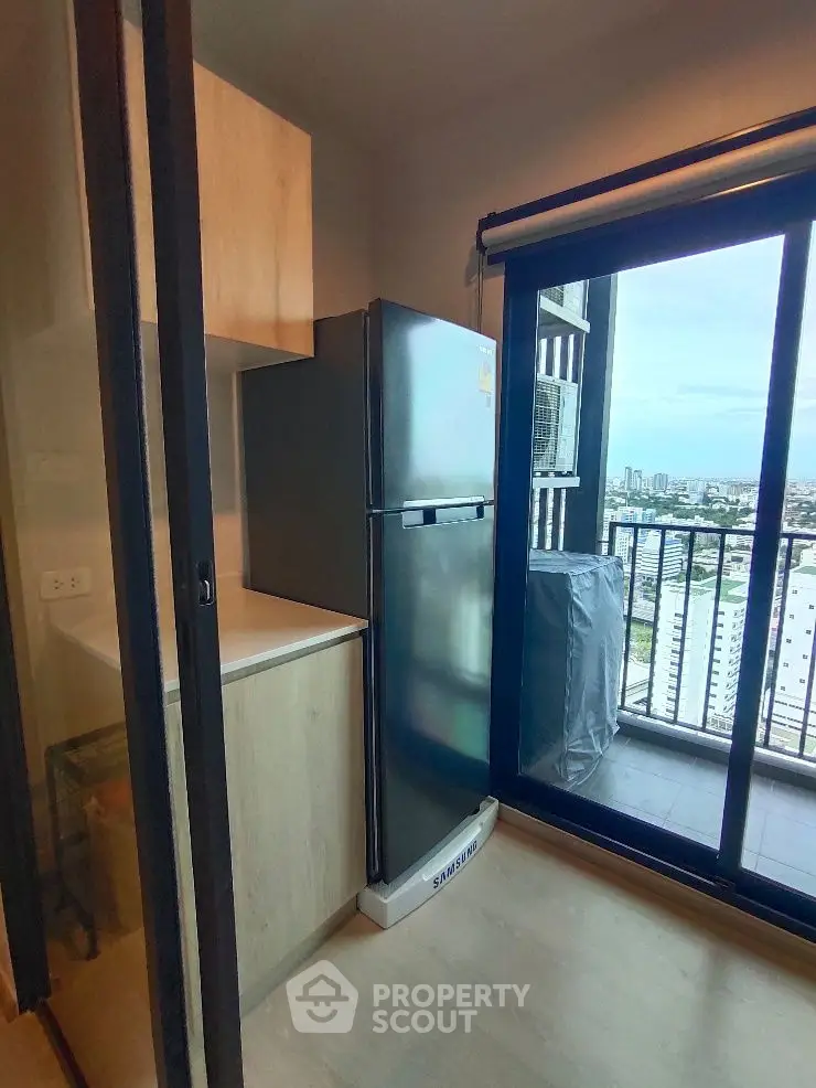 Modern kitchen with balcony view and sleek refrigerator in urban apartment.