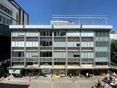 Modern commercial building with large windows and rooftop structure in urban setting.