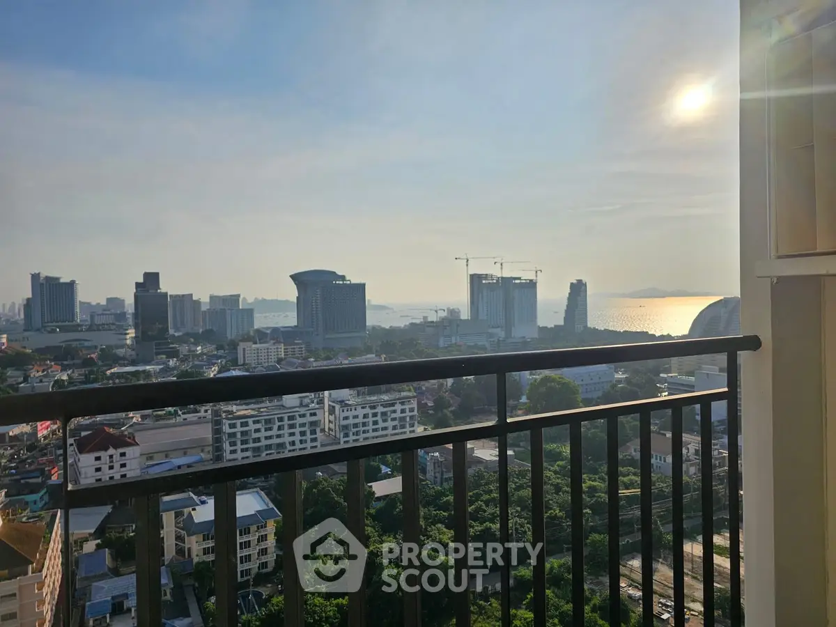 Stunning cityscape view from a high-rise balcony at sunset, showcasing urban skyline and ocean horizon.