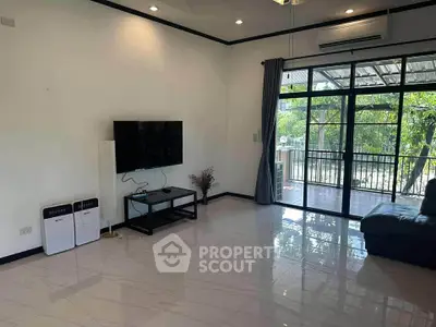 Spacious living room with modern decor and large windows opening to a balcony with a view.