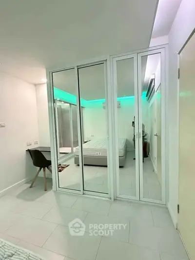 Modern bedroom with mirrored closet doors and ambient lighting