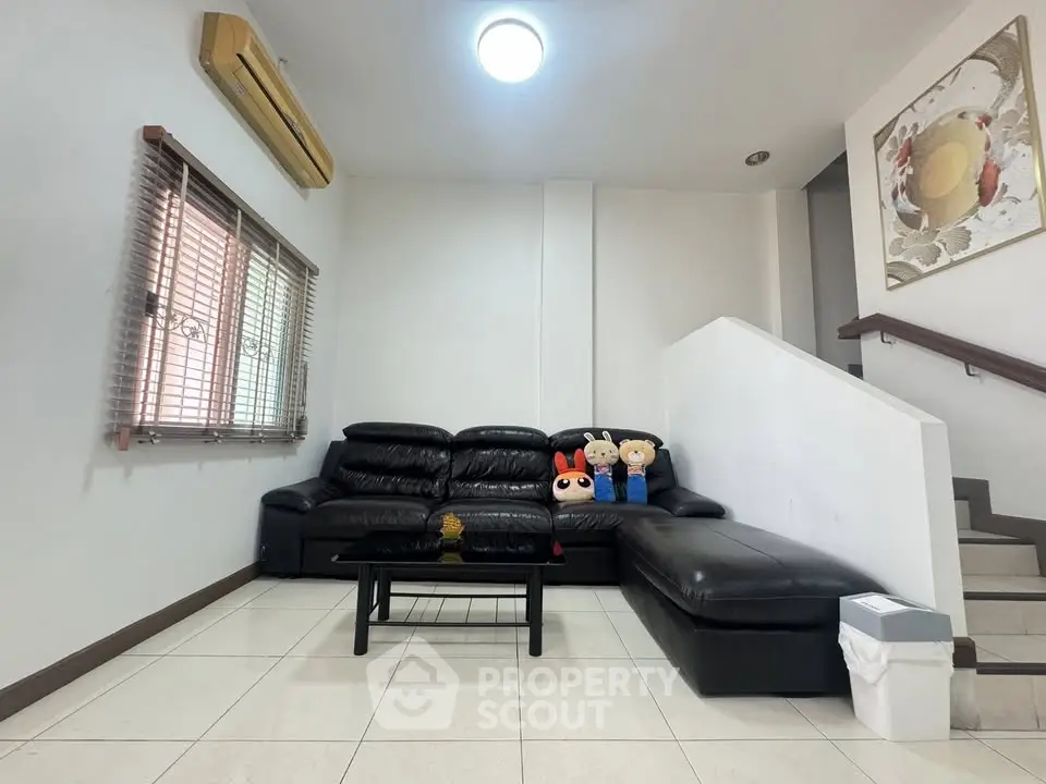 Modern living room with black leather sofa and stylish decor in a cozy home setting.