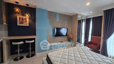 Modern bedroom with stylish decor, featuring a mounted TV, cozy seating, and elegant lighting.