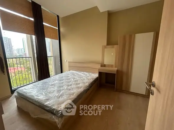 Modern bedroom with large windows and city view, featuring a bed and wardrobe.