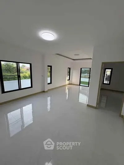 Spacious empty living room with large windows and glossy tiled floors