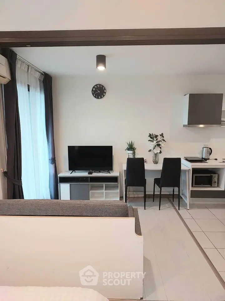 Modern open-plan living room with sleek kitchen and dining area, featuring stylish decor and natural light.