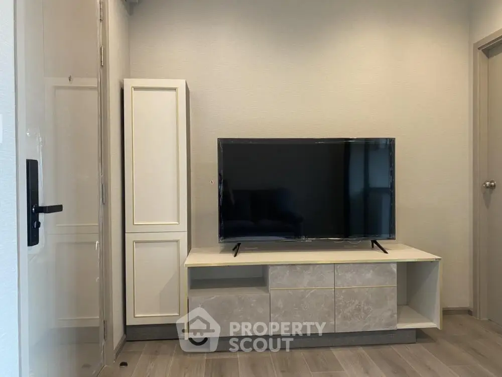 Modern living room with sleek TV stand and flat-screen TV, featuring minimalist design and neutral tones.