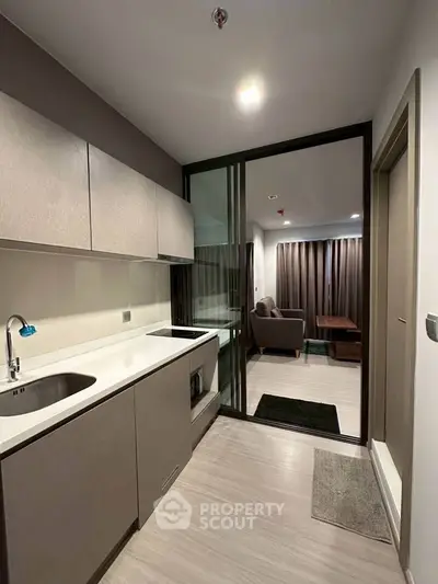 Modern kitchen with sleek cabinetry and open layout leading to cozy living room.