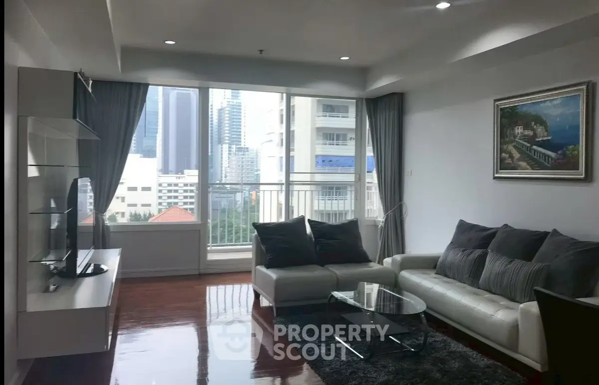 Spacious living room with modern decor and city view, featuring large windows and elegant furnishings.