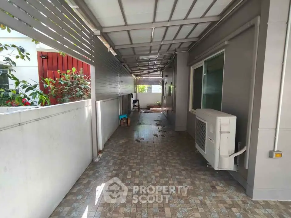 Spacious covered outdoor corridor with tiled flooring and air conditioning unit.