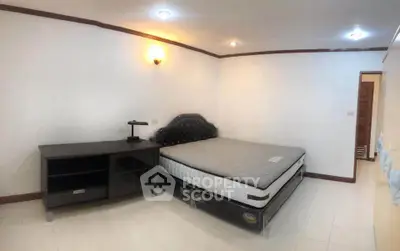 Spacious bedroom with elegant bed and modern furniture in a well-lit room.