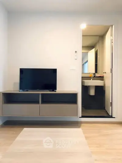 Modern living room with wall-mounted TV and view into a sleek bathroom.