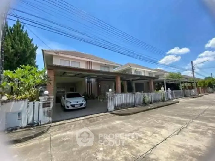 Charming suburban house with driveway and lush greenery under a clear blue sky.