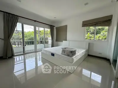 Spacious bedroom with large windows and balcony access, offering abundant natural light and serene views.