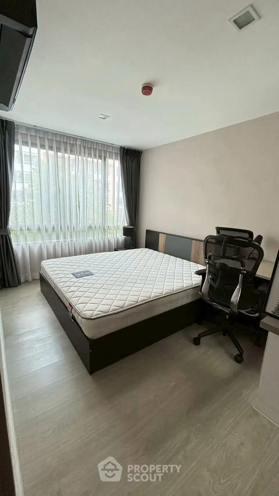 Spacious bedroom with large window and modern furnishings in a stylish apartment.
