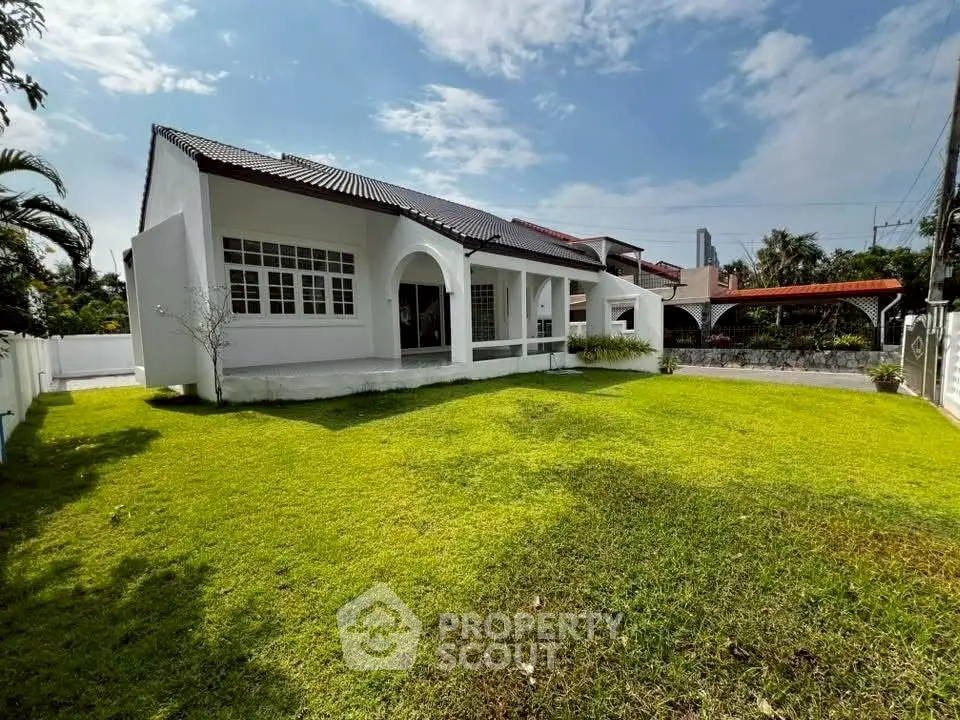 Charming single-story house with spacious green lawn and classic architecture.