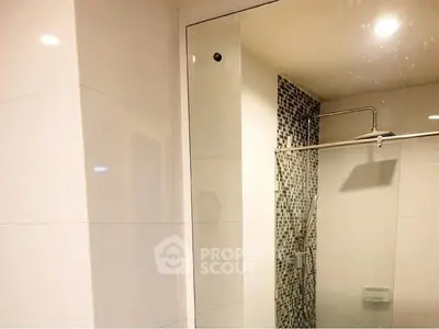 Modern bathroom with sleek glass shower and mosaic tile accent wall.