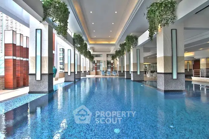 Luxurious indoor pool with modern design and lush greenery in a high-end residential complex.