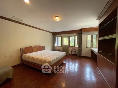 Spacious bedroom with large windows and wooden flooring, perfect for comfort and relaxation.