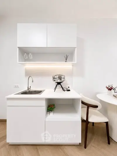 Modern minimalist kitchen with sleek white cabinetry and integrated sink, perfect for contemporary living.