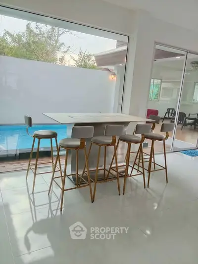 Modern kitchen with sleek bar stools and pool view, perfect for entertaining.